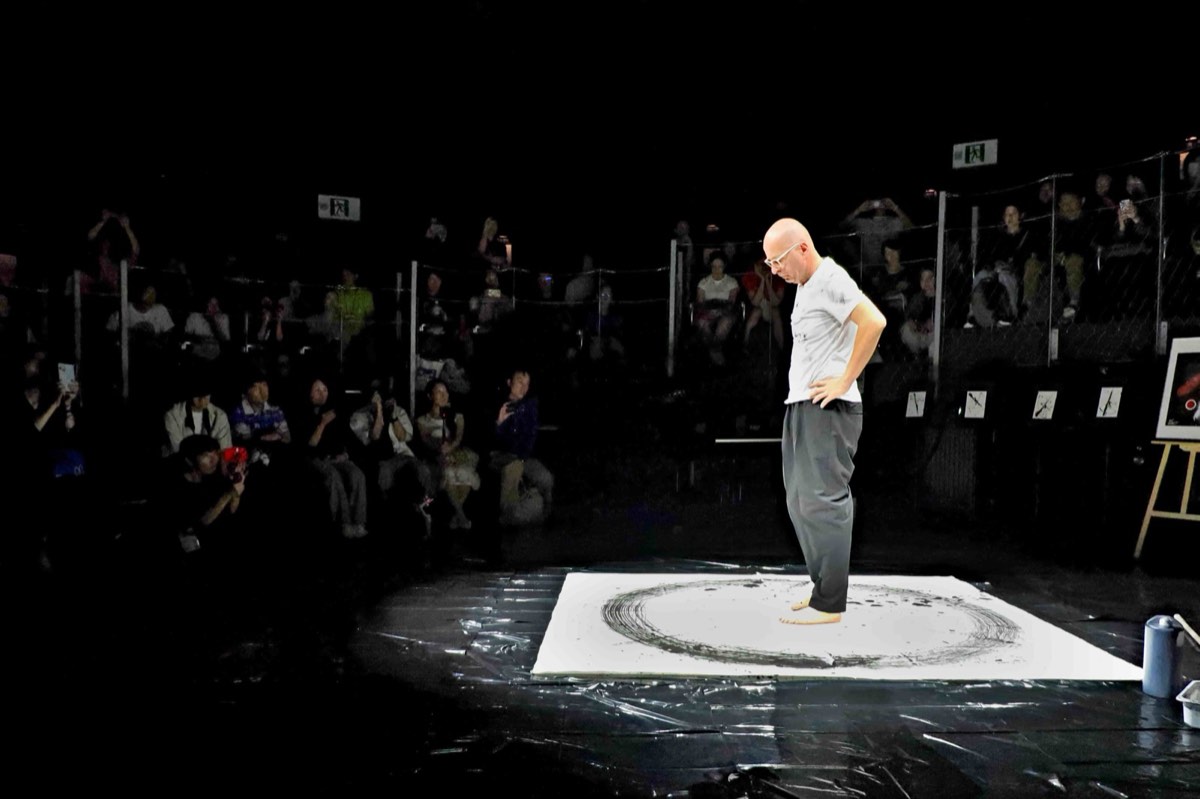 Vit on the white stage, the ring completed, audience watching from the dark